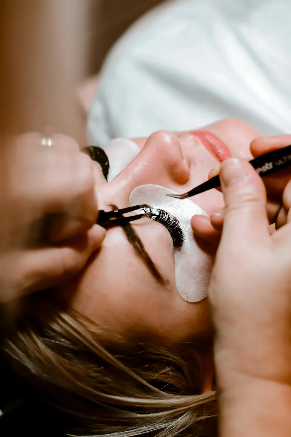 Applying lash extensions with tweezers